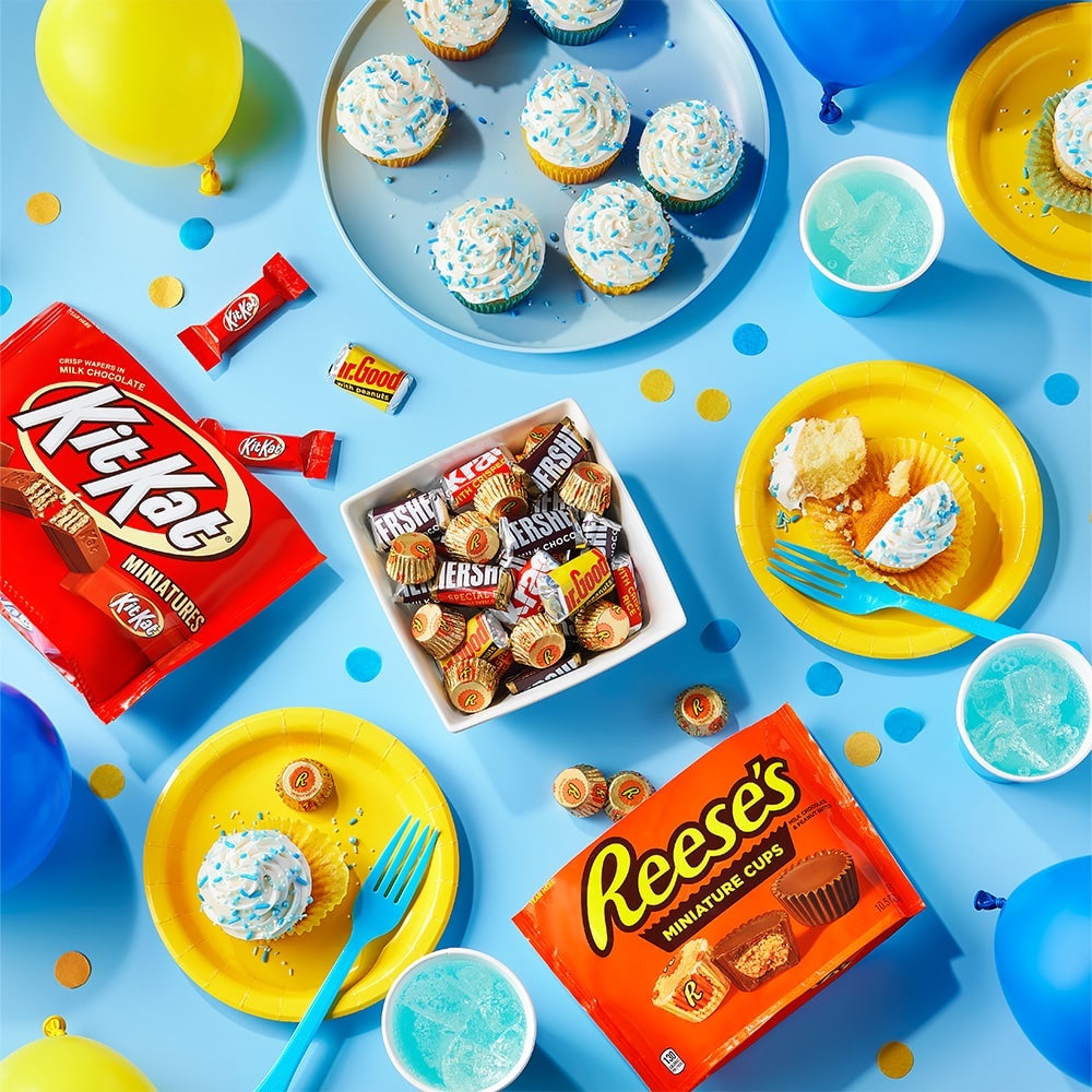 table filled with party decorations and assorted hersheys candy