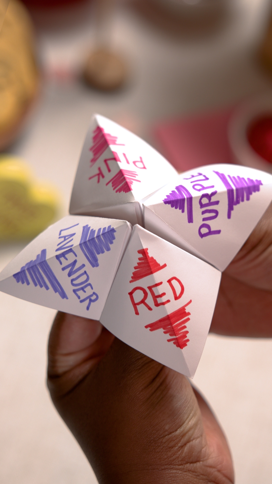 person interacting with a paper fortune teller craft